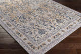 Close-up of Barrie Area Carpet on dark wood floor. The rug has a traditional floral pattern in brown, charcoal, and cream. Corner