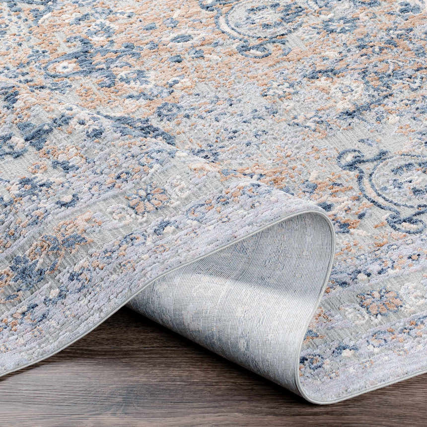 Close up of the Barrie Area Carpet featuring a traditional blue, cream, and beige floral pattern. Fold