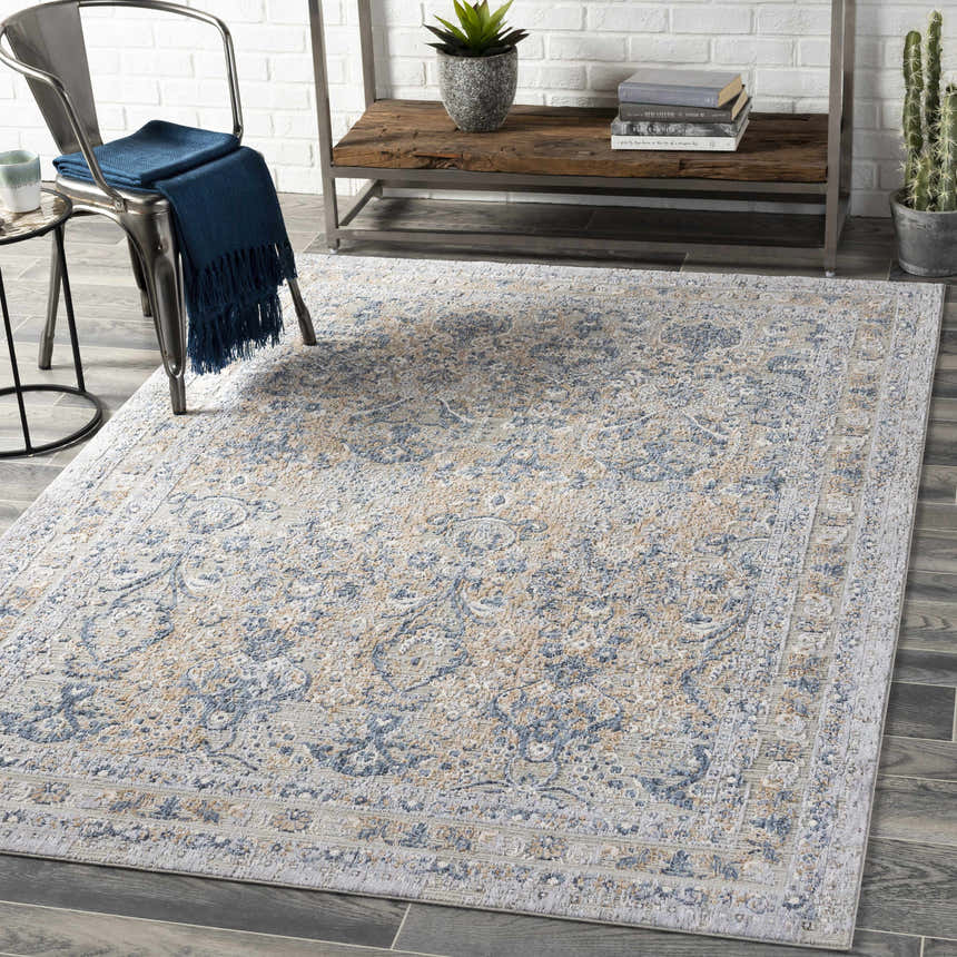 Farmhouse living room scene with a Barrie Area Carpet in beige, blue, and gray tones on dark wood floors. Metal chair and shelf. Roomscene-Rectangle