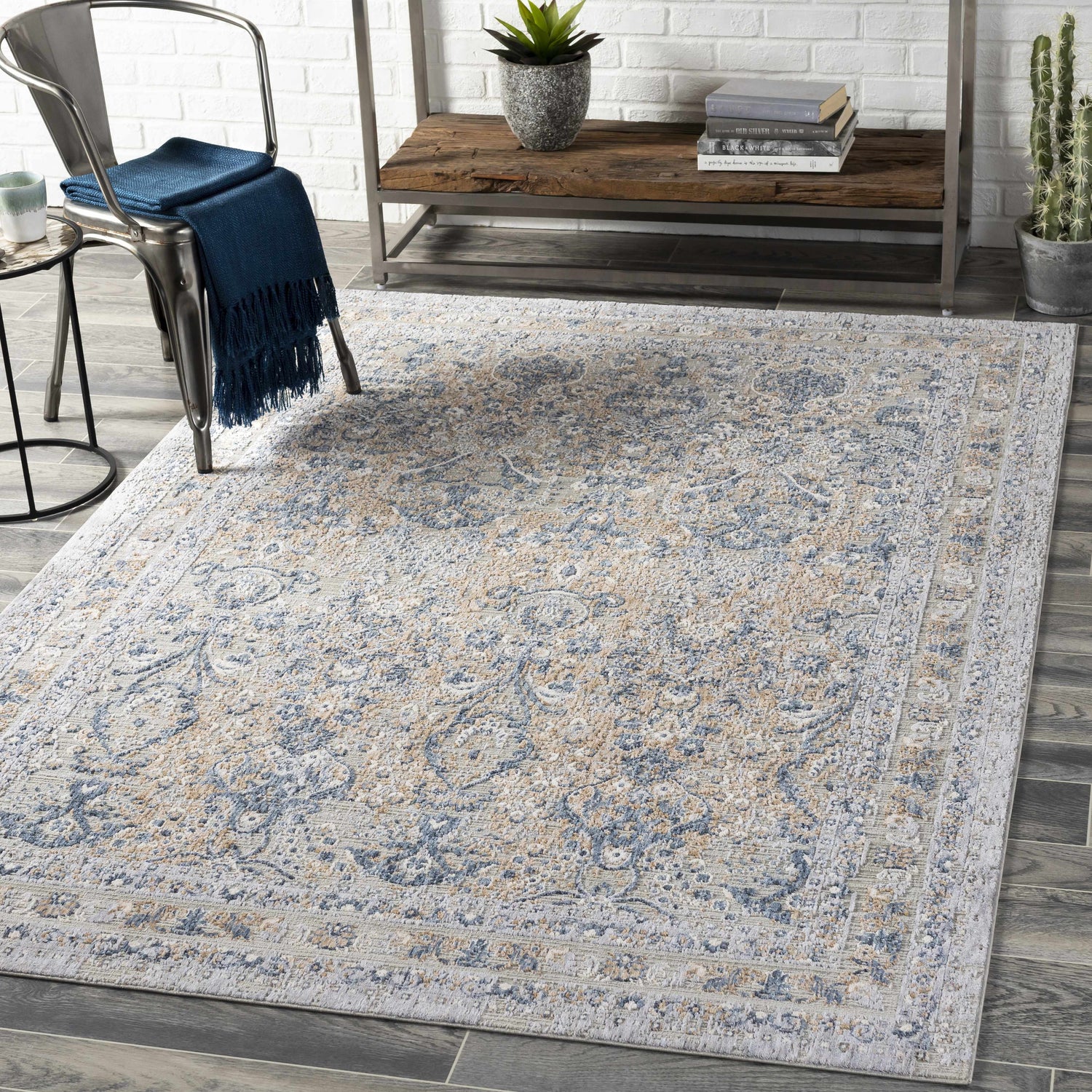 Farmhouse living room scene with a Barrie Area Carpet in beige, blue, and gray tones on dark wood floors. Metal chair and shelf. Roomscene-Rectangle
