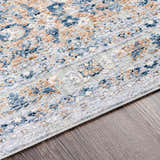 Close-up of the Barrie Area Carpet. Features a traditional pattern in cream, brown, and blue on a wood floor. Texture