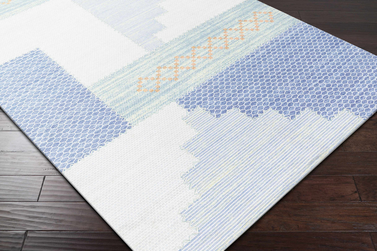 Close-up of the Bishopstoke Carpet, a hand-woven rug with blue, cream, and peach geometric patterns on a dark wood floor. Corner