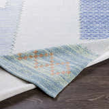 Close-up of Bishopstoke Carpet showing blue, cream, and peach tones with a hand-woven texture on dark wood floor. Fold