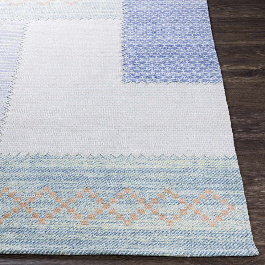 Close-up of the Bishopstoke Carpet, a hand-woven rug with blue, cream, and peach tones. Features a geometric pattern. Front
