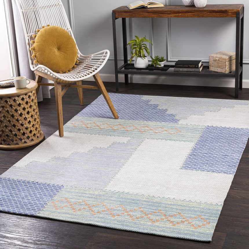 Coastal room scene with blue, cream Bishopstoke Carpet, white chair, and wood accents. Roomscene-Rectangle