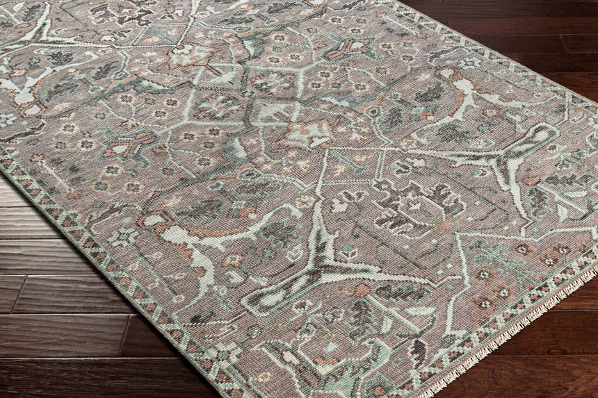 Close-up of the hand-knotted Bugasan Area Rug. Plum, tan, teal, and gray tones create a traditional, bohemian pattern. Corner