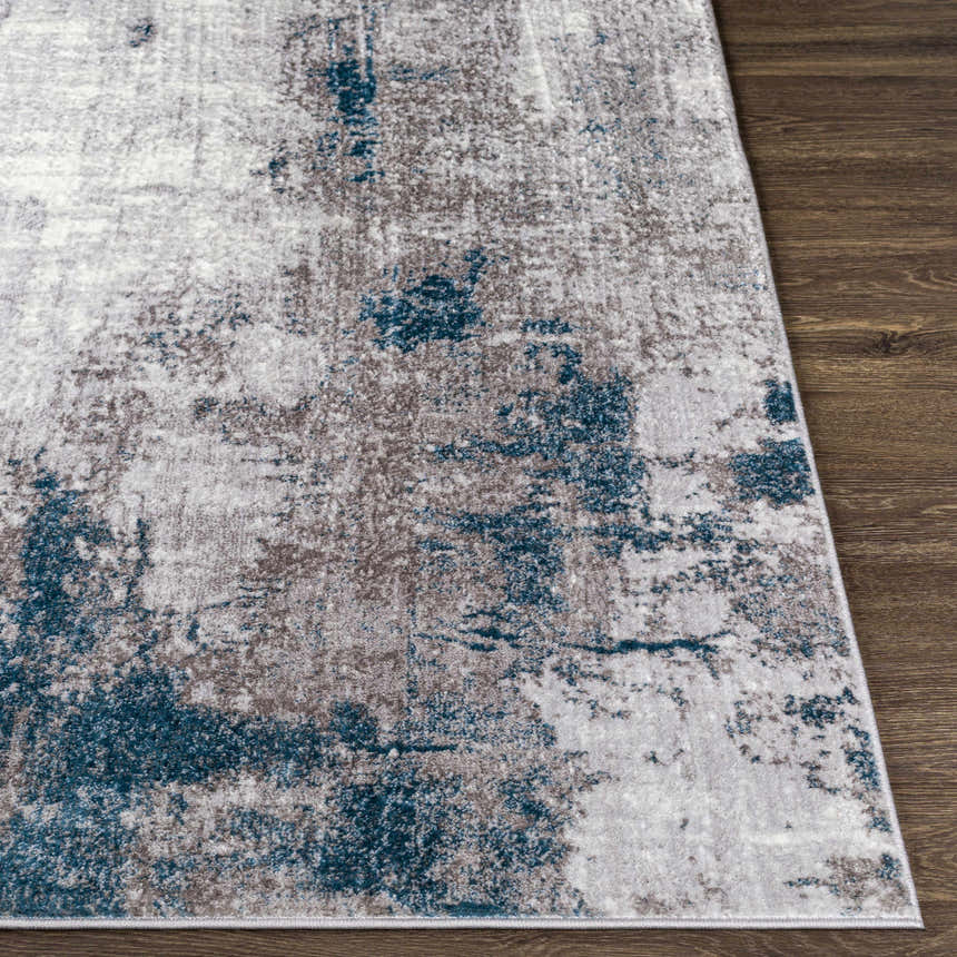 Close-up of the Bugho Area Rug, showcasing its cream, gray, and teal abstract design on a dark wood floor. Front
