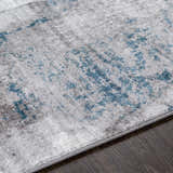 Close-up of the Bugho Area Rug, a contemporary rug with a cream, gray, and denim abstract design. Texture