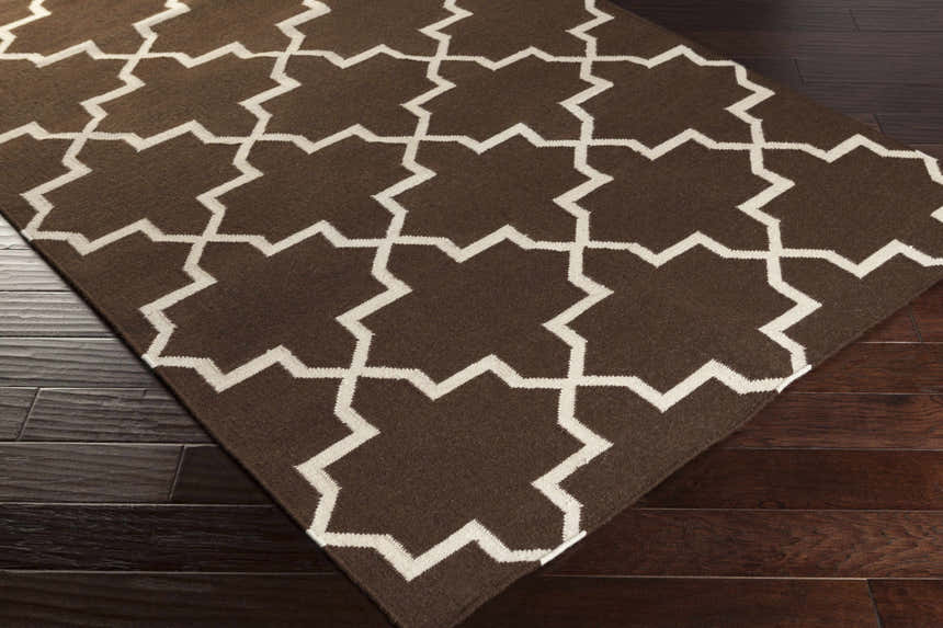 Close-up of the Bullock Area Carpet showing a brown wool rug with an ivory geometric pattern. Corner