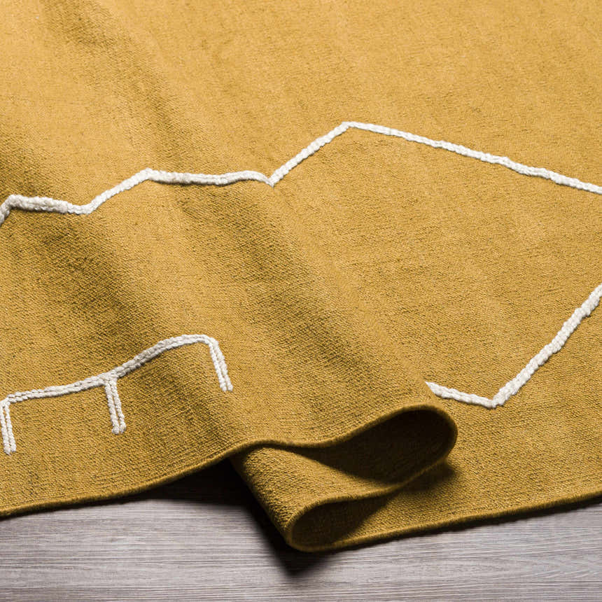 Close-up of the hand woven Bushra Area Rug in mustard yellow with a geometric white pattern. Fold