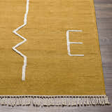 Close up of the hand woven Bushra Area Rug; gold with white geometric design and fringe. Front