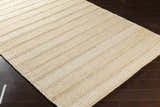 Close-up of the Bywong Area Rug. Beige and off-white jute rug with a hand-woven, striped texture. Corner