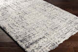 Close-up of the Calsib Area Rug, a shag rug in cream and black, on dark wood flooring. Corner