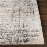 Close up of the Calsib Area Rug showing its cream, light beige, and black shag texture on a dark wood floor. Front