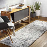Hallway scene with the Calsib Area Rug in black, cream, and gray. Modern cabinet, chair, and plants create a stylish, inviting space. Roomscene-Runner