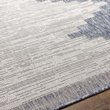 Close-up of the Djugun Blue Outdoor Rug showing its woven texture and geometric pattern in blue, gray, and off-white. Texture