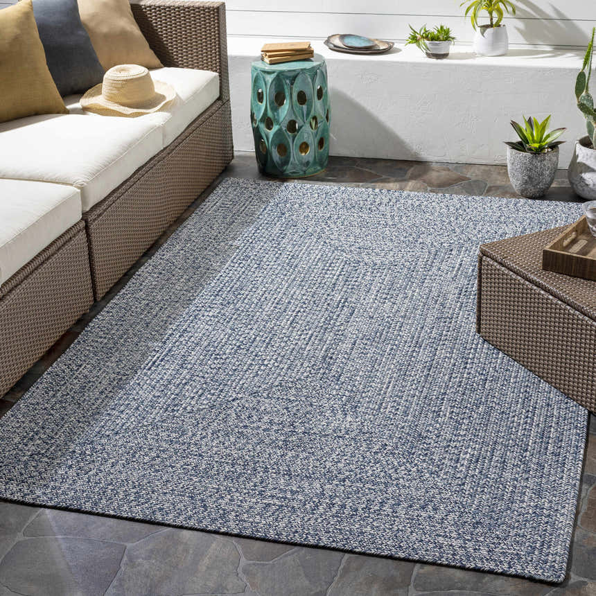 Outdoor patio scene with Blue Braided Faux Jute Rug, wicker furniture, and plants. Stylish and inviting space. Roomscene-Rectangle