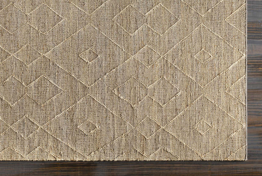 Close-up of the Carine Jute Area Rug showing beige color and geometric diamond pattern with textured, hand-woven construction. Corner