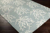 Close-up of Carversville Ice Blue Botanical Wool Rug with ivory coral pattern on dark wood floor. Corner