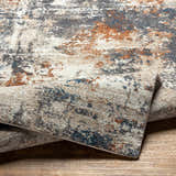 Close-up of the Chetwynd Abstract Thick Rug showing its blue, brown, cream, and gray distressed pattern and texture. Fold