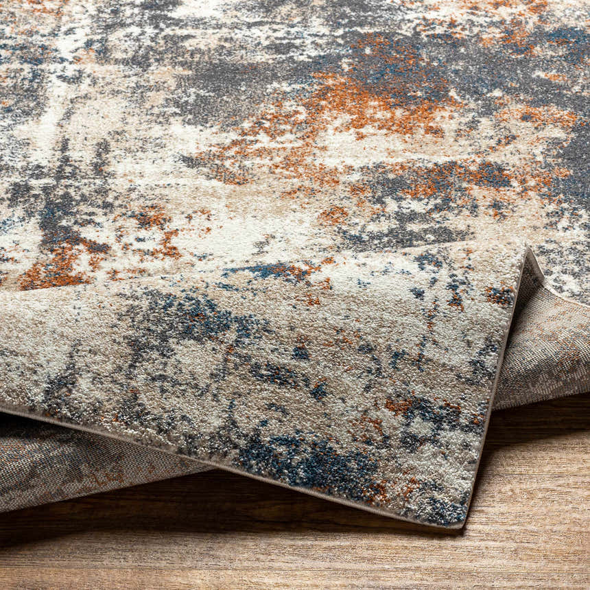 Close-up of the Chetwynd Abstract Thick Rug showing its blue, brown, cream, and gray distressed pattern and texture. Fold