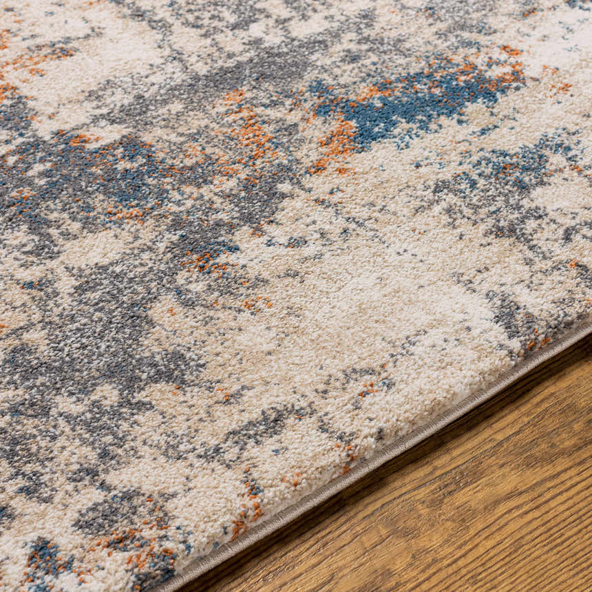 Close-up of the Chetwynd Abstract Thick Rug. Features blue, brown, cream, coral, and gray abstract pattern. Texture