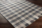 Close-up of the hand-woven Chilliwack Gray Plaid Wool Rug showing charcoal, cream, and gray tones with fringe detail. Corner