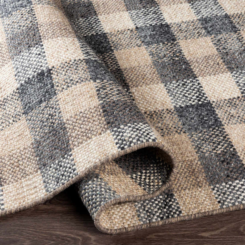 Close-up of the hand-woven Chilliwack Gray Plaid Wool Rug showing charcoal, cream, gray, and tan colors and textured weave. Fold