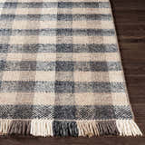 Close-up of the hand-woven Chilliwack Gray Plaid Wool Rug showing charcoal, cream, and gray tones with fringed edge. Front