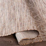 Close-up of the Coolville Brown Flatweave Area Carpet showing its woven texture and neutral brown, cream, and tan colors. Fold