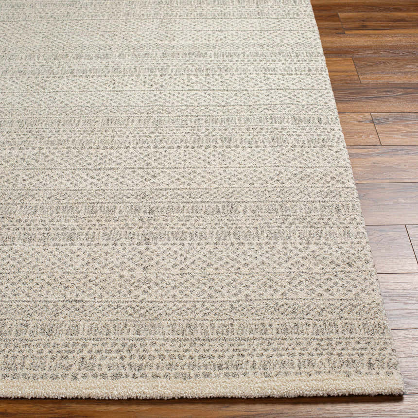 Close-up of the Cinco Luxe Rug showing its bone and gray geometric pattern and soft, textured pile on a wood floor. Front