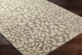 Close-up of the Beachhouse Beige Circa Leopard Print Area Rug on dark wood floors. Hand-tufted 100% wool rug. Corner