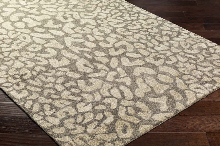 Close-up of the Beachhouse Beige Circa Leopard Print Area Rug on dark wood floors. Hand-tufted 100% wool rug. Corner