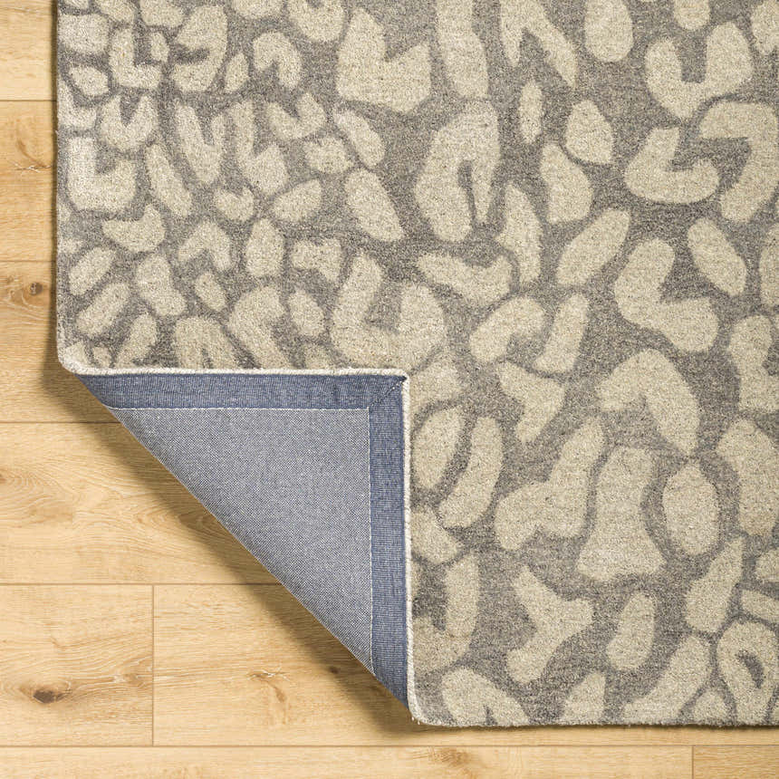 Close-up of the Circa Leopard Print Area Rug showing the beige and gray wool texture and backing. Fold
