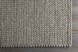 Close-up of the hand woven Cirencester Area Rug in ivory and medium gray, showing the natural fibers and textured weave. Corner