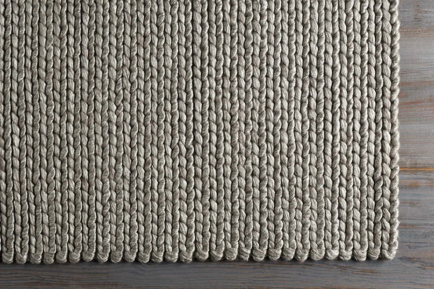 Close-up of the hand woven Cirencester Area Rug in ivory and medium gray, showing the natural fibers and textured weave. Corner
