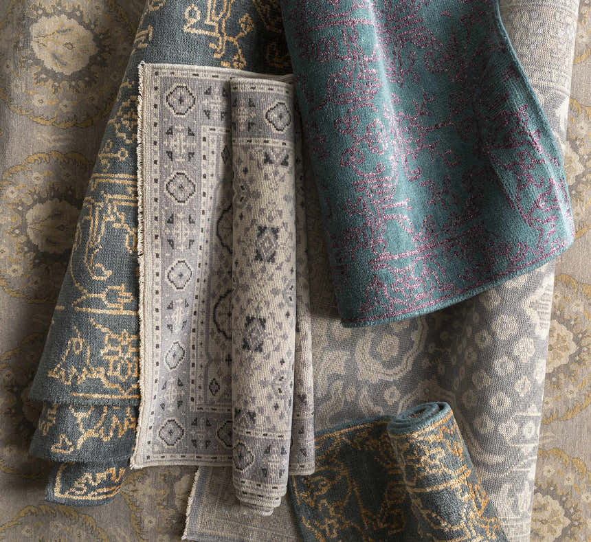 Close-up of rolled Haleiwa Clearance Rugs in camel, dark green, and taupe. Hand-knotted wool with farmhouse and traditional patterns. Styleshot