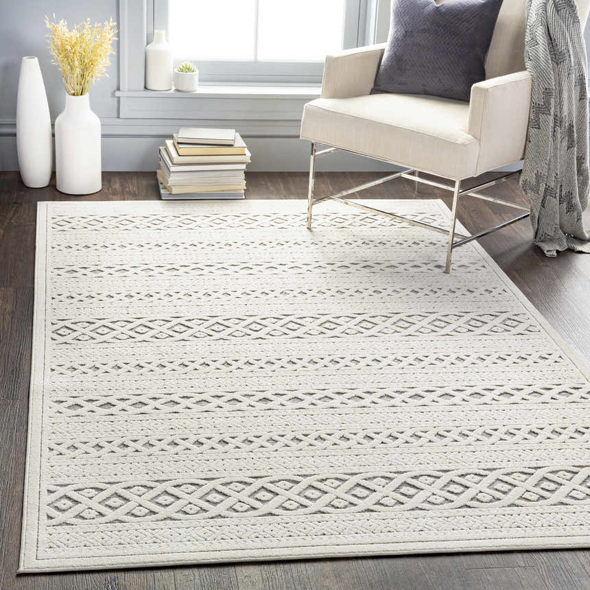 Living room scene with a Clenchwarton Textured Beige Rug, light chair, and dark wood floors. Neutral, cozy aesthetic. Roomscene-Rectangle