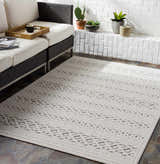 Living room scene with a Clenchwarton Textured Beige Rug, white sofa, brick wall, and potted plants. Roomscene-Rectangle