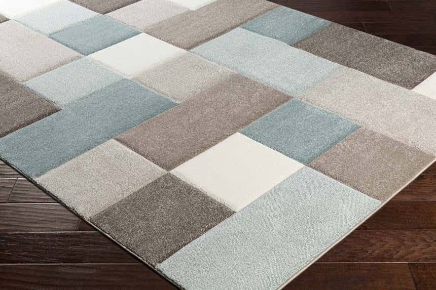 Close-up of the Clinton Area Rug, a contemporary rug with aqua, brown, ivory, and taupe geometric block pattern. Corner