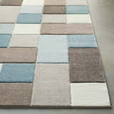 Close-up of the Clinton Area Rug showing its aqua, brown, ivory, and taupe block pattern and soft texture. Front