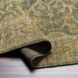 Close-up of the hand-knotted Clunes Area Rug, showcasing its traditional black, brown, green, and yellow pattern and wool texture. Fold