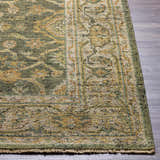 Close-up of the hand-knotted Clunes Area Rug. Features a traditional oriental design in grass green, light beige, and brown wool. Front