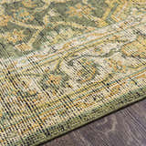 Close-up of the hand-knotted Clunes Area Rug. Wool rug with a traditional pattern in grass green, yellow, light beige, and black. Texture