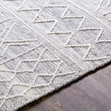 Close-up of Gray Clintwood Wool Tassel Carpet showing geometric pattern and textured weave in charcoal, cream, oatmeal, and white. Texture