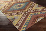 Close-up of the hand-woven Clutier Clearance Rug. Features a geometric pattern in beige, blue, brown, mustard, and rose. Corner