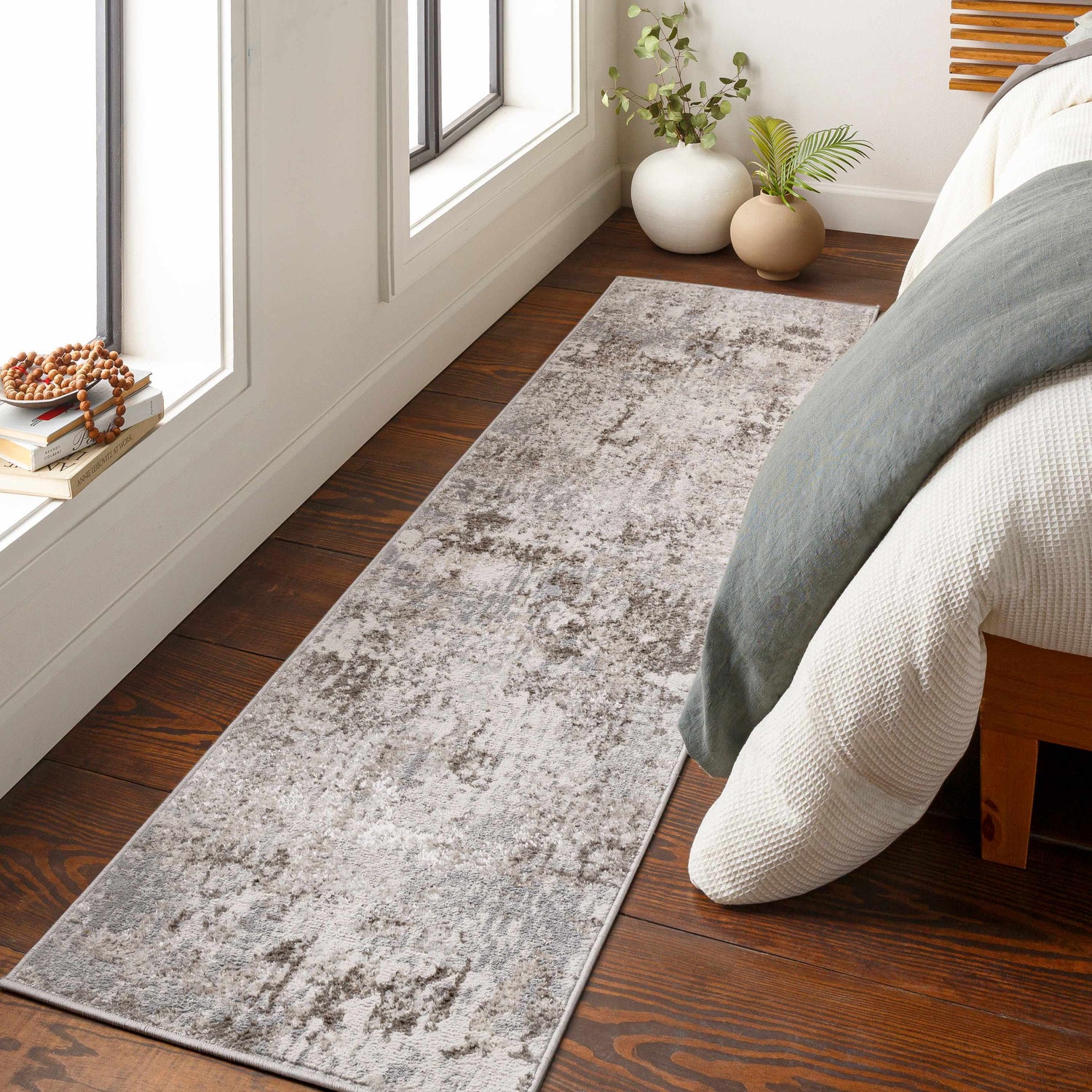 Bedroom scene with a charcoal and gray Calvinia Area Rug, wood floors, and neutral bedding. Roomscene-Runner
