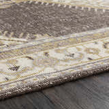Close-up of the hand-knotted Clyo Carpet. Brown, charcoal, and off-white wool farmhouse rug on dark wood floor. Texture