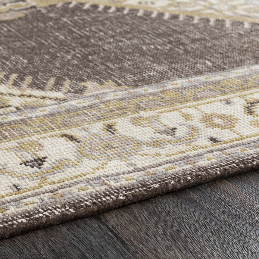 Close-up of the hand-knotted Clyo Carpet. Brown, charcoal, and off-white wool farmhouse rug on dark wood floor. Texture