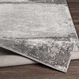 Close-up of the Coombs Area Rug, showcasing its charcoal, gray, and light gray abstract design and machine-woven texture. Fold